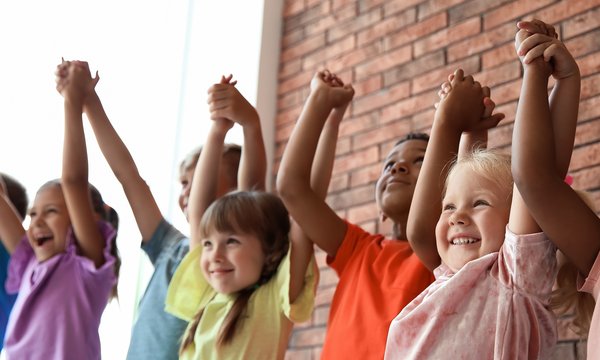 Eine Gruppe Kinder hält sich mit ausgestreckten Armen an den Händen.