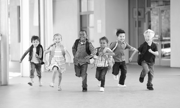 Eine Gruppe von Kindern, die Rucksäcke tragen, kommen freudig angerannt.