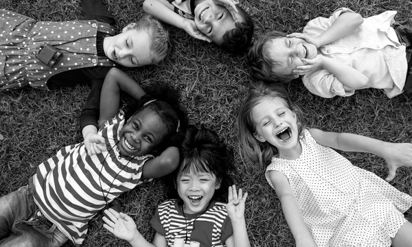 Mehrere lachende Kinder liegen im Kreis nebeneinander.